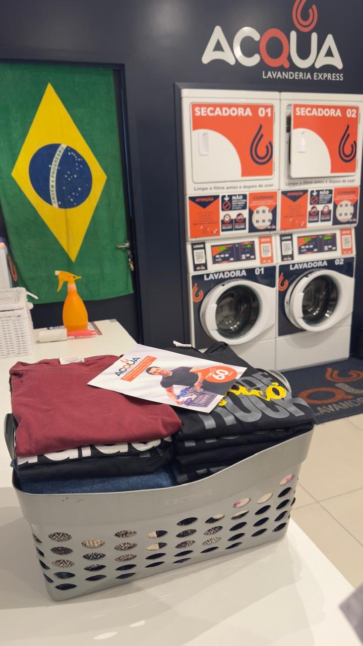 Cesto de roupa lavada e dobrada, com as máquinas da Acqua Lavanderia Express ao fundo